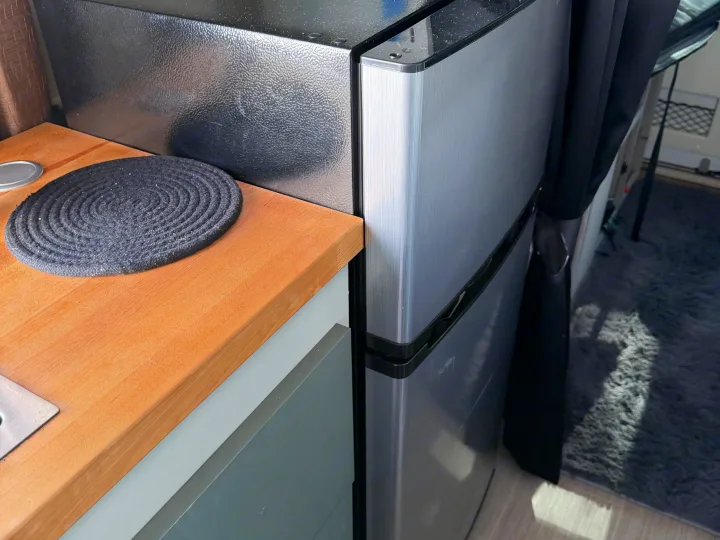 RV rental compact kitchen featuring a mini-fridge, wooden counter with a mat, and gray rug, ideal for small spaces.. Dodge 3500shc 2021