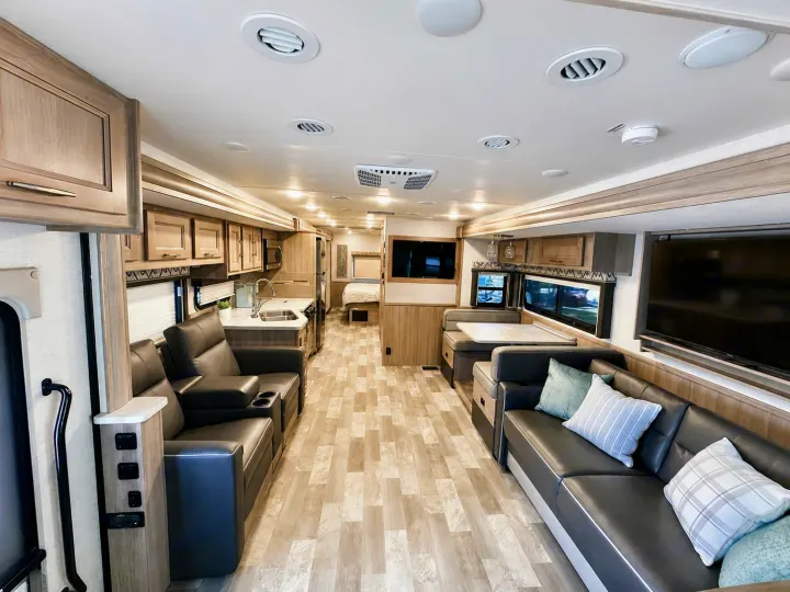 Spacious RV rental interior with modern kitchen, living area featuring recliners and sofa, and a comfortable dining booth.. Coachmen Mirada 2019