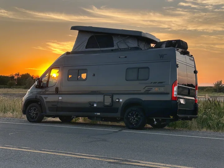 Gray Winnebago Solis camper van with its pop-top open, parked by the road at sunset. Ideal for an RV rental adventure.. Winnebago Solis 59PX 2027