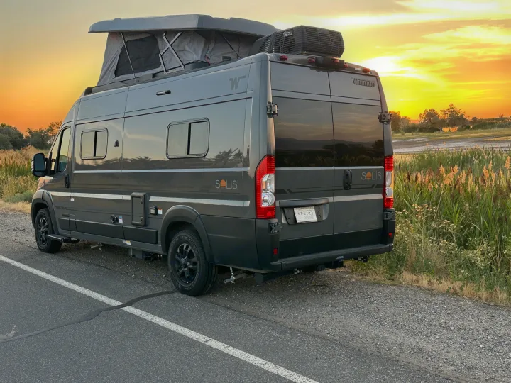 Gray Winnebago Solis camper van with pop-top, perfect for an RV rental adventure, parked by a scenic roadside at sunset.. Winnebago Solis 59PX 2027