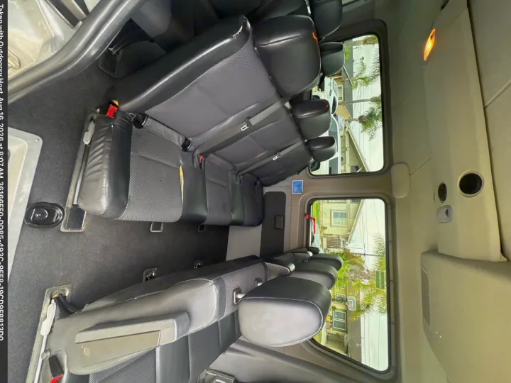 RV rental van interior with multiple rows of black and grey passenger seating, featuring seatbelts and large windows.. Mercedes-Benz sprinter 2013