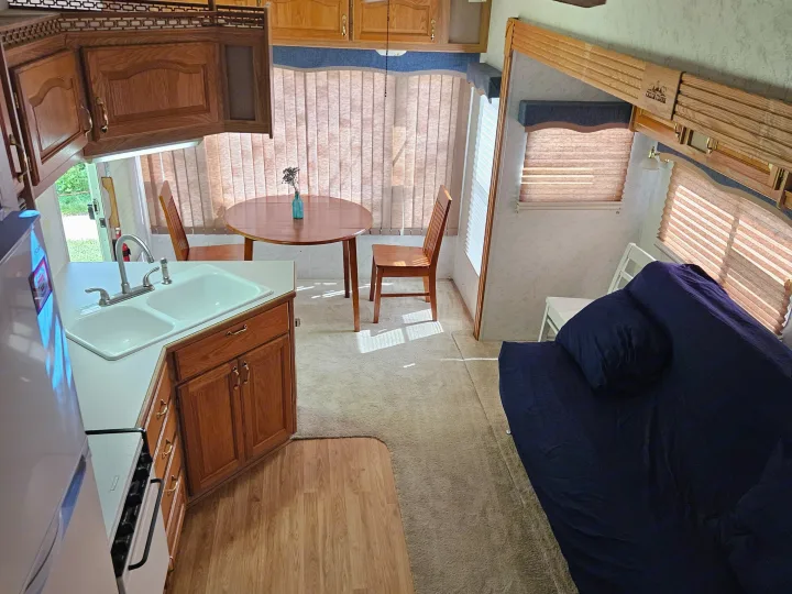 Explore this rv rental's interior: a kitchen with double sink, dining table, and blue sofa bed for comfy trips.. Cedar Creek Cedar Creek Fifth Wheel 2002
