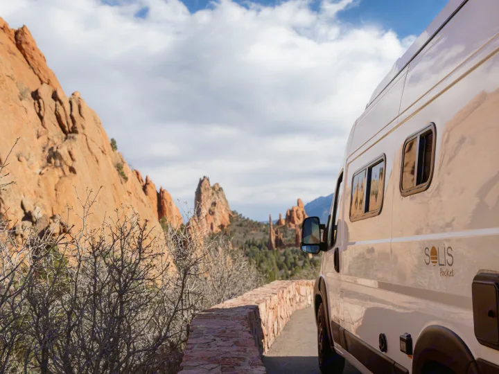 "Solis Pocket" RV rental camper van parked on a scenic road with red rock mountains under a cloudy sky, ideal for outdoor travel.. Winnebago Solis 2025