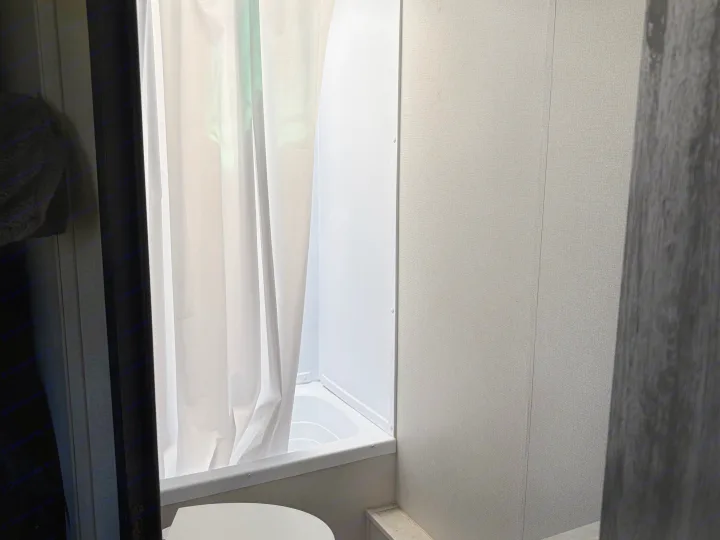 Compact RV rental bathroom: white shower, tub, and curtain. Functional space for travel adventures.. Keystone RV Hideout 2021