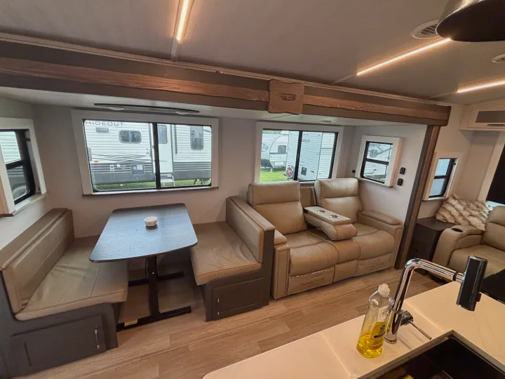 Spacious RV rental interior featuring a dining booth, reclining theater seating, and a modern kitchen area.. Keystone RV Bullet Premium 2025
