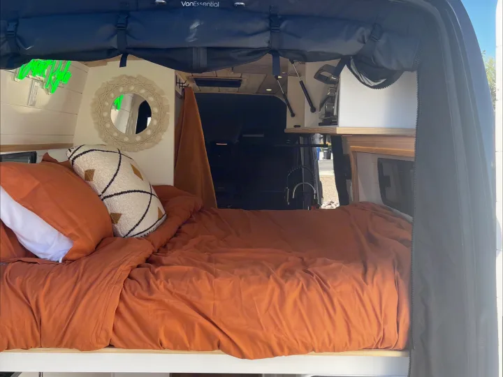 Cozy camper van interior for your next rv rental, featuring a bed, 'Happy Place' neon sign, and a compact kitchen faucet.. Mercedes Sprinter 2500 2019