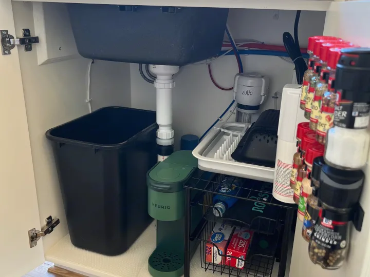 Efficient under-sink storage in an RV rental kitchen: trash can, Keurig, water filter, dish rack, and spices.. Mercedes Sprinter 2500 2019