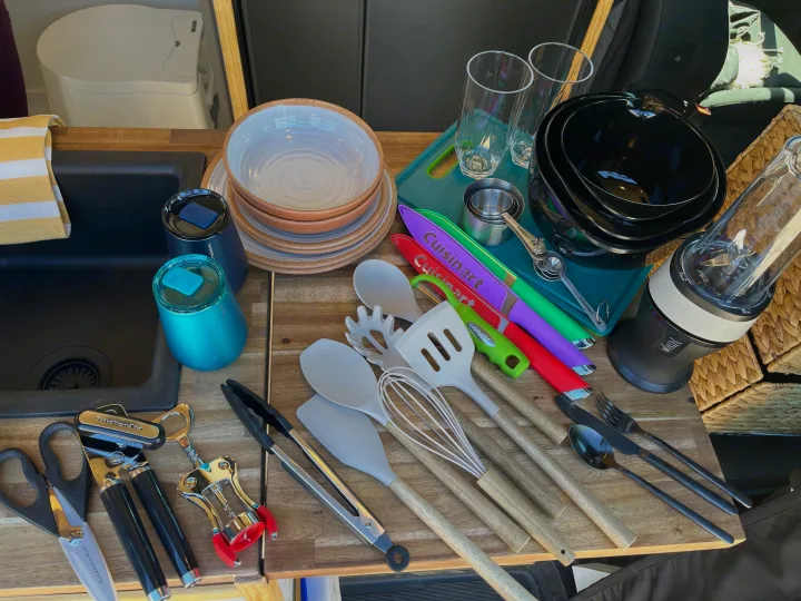 RV rental kitchen setup: Dishes, colorful utensils, measuring tools, blender, and glasses neatly on a wooden counter.. Mercedes Sprinter 2500 2019