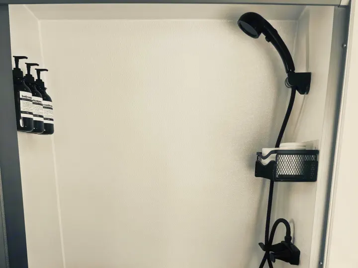 Compact rv rental shower featuring body wash, shampoo, conditioner, a black showerhead, and a mesh caddy with essentials.. Mercedes Sprinter 2500 2019