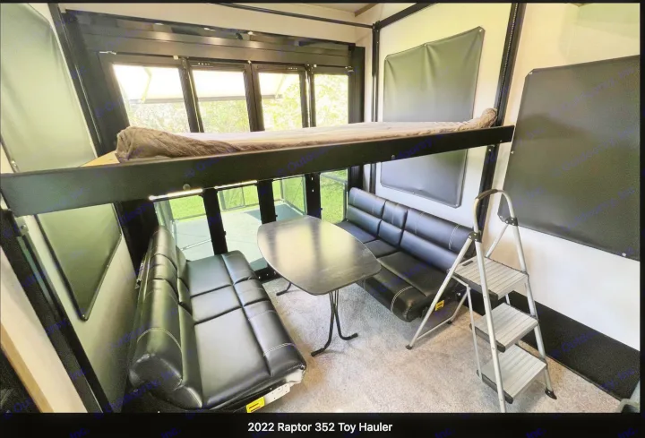 Spacious toy hauler rv rental interior features a bunk bed, dinette, and large windows revealing green outdoors.. Keystone RV Raptor Toy Hauler 2022