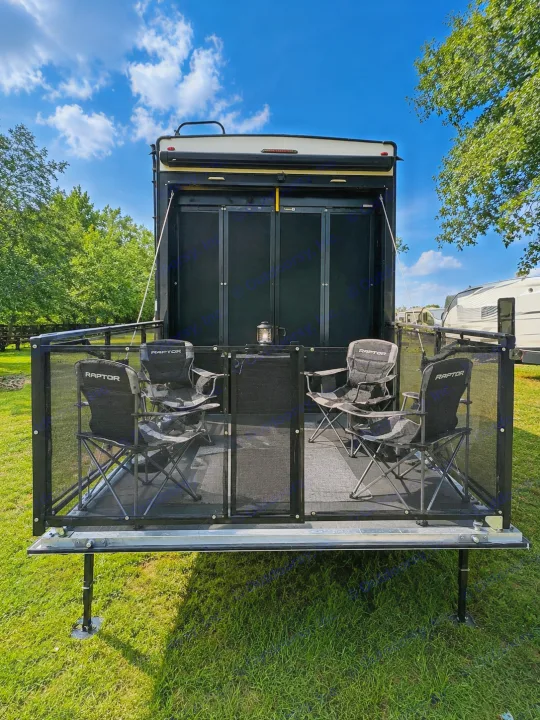 Experience this RV rental's toy hauler patio: a screened deck with chairs and a lantern, perfect for campground relaxation.. Keystone RV Raptor Toy Hauler 2022