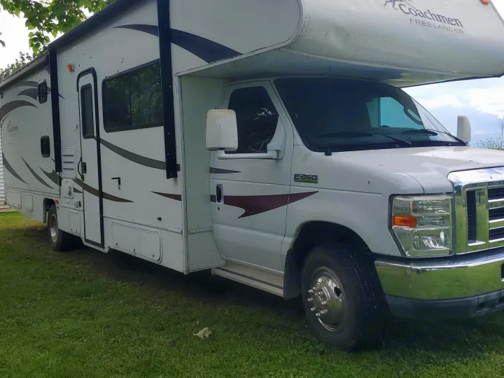 This white Coachmen Freelander RV rental is a Class C motorhome with brown decals, parked on green grass, ready for adventure.. CoachMen Freelander 2012