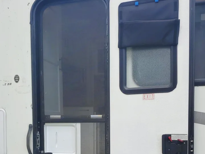 View of an RV rental's open white main door with privacy shade and black screen door, revealing the interior steps.. CoachMen Freelander 2012