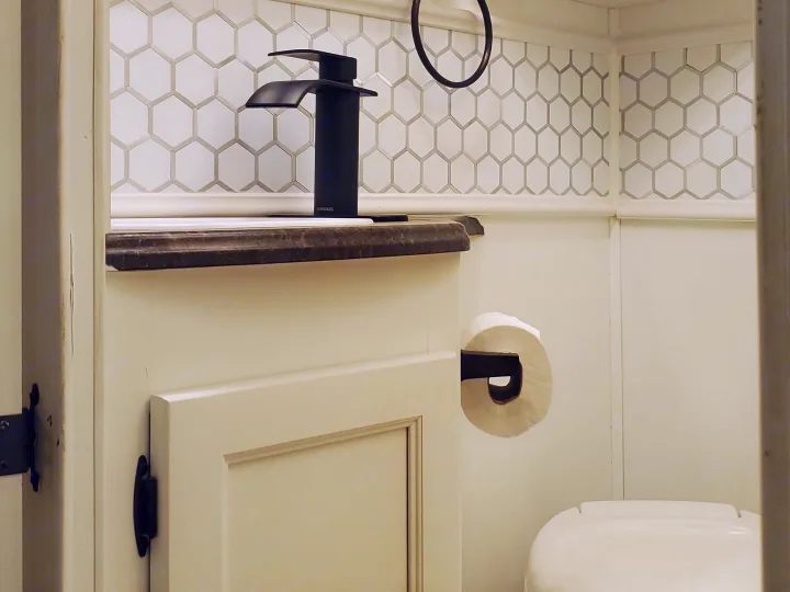 Modern and compact bathroom inside an RV rental, featuring white hexagon tiles, black fixtures, and a sleek faucet.. CoachMen Freelander 2012