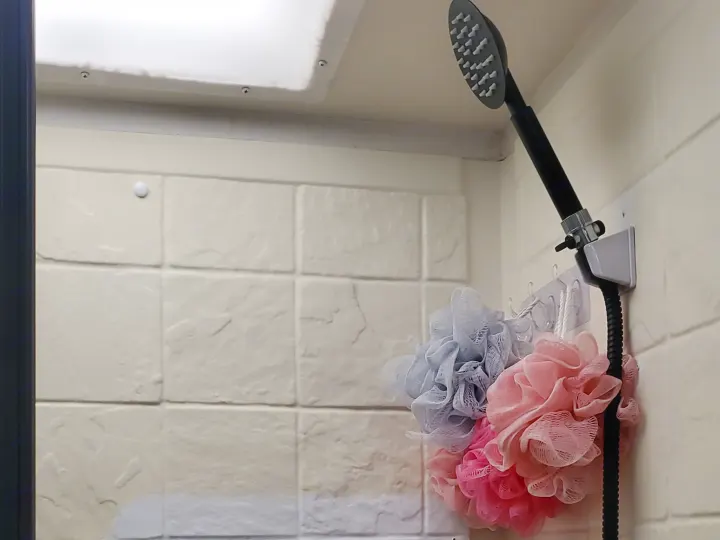 RV rental shower featuring a handheld showerhead, colorful loofahs, and textured interior walls for a compact bathroom.. CoachMen Freelander 2012