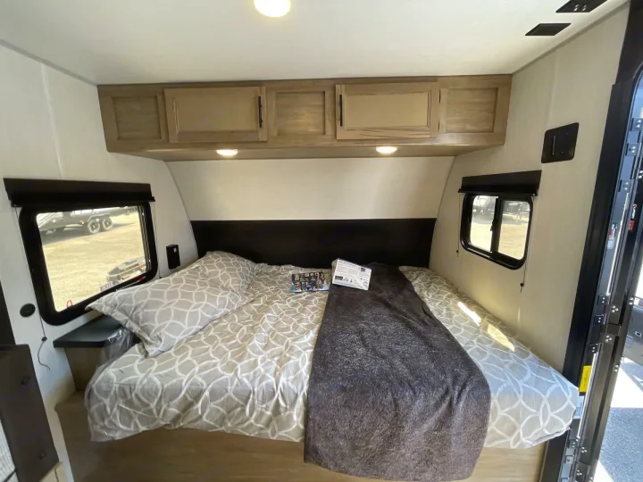 Cozy RV rental bedroom with a comfortable bed, overhead cabinets, and windows, ready for a relaxing trip.. Forest River Cherokee Wolf Pup 2026