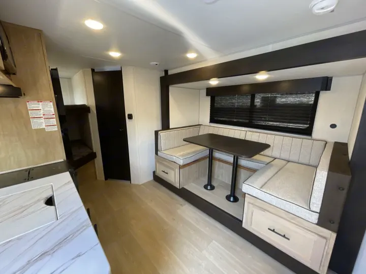 RV rental interior: bright space with light wood floors, comfy dinette, storage, kitchen counter, & bunks. Ready for adventure.. Forest River Cherokee Wolf Pup 2026