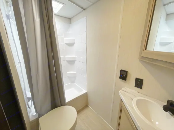 Clean RV rental bathroom featuring a white shower/tub, toilet, and vanity with sink, ideal for travel & camping adventures.. Forest River Cherokee Wolf Pup 2026