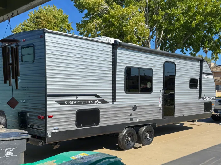 Gray and white Catalina Summit Series RV rental parked outdoors, showing its side profile, windows, and awning.. Coachmen Catalina 261 bh 2026