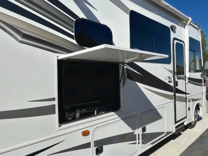 White RV rental's side, showcasing an open compartment with an outdoor TV and entertainment system. Perfect for your road trip!. Jayco Alante 2018
