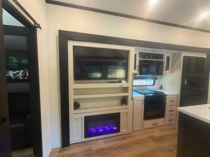 Explore this modern RV rental! Features a well-equipped kitchen, TV/fireplace entertainment center, and private bunk room access.. Forest River Sabre 2025