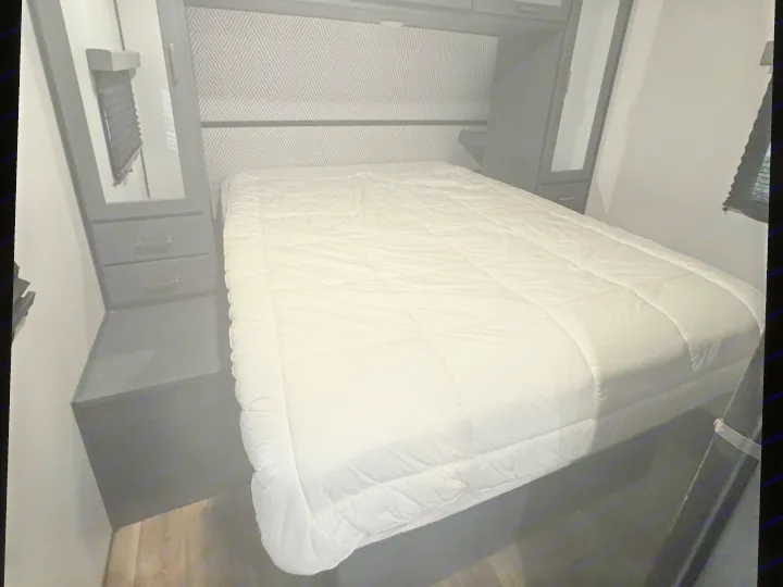 Cozy RV rental bedroom with a comfortable bed, geometric headboard, and overhead storage, perfect for your next adventure.. Keystone RV Bullet Ultra Lite 2022