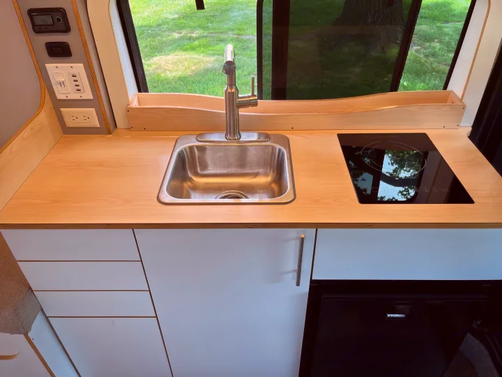 RV rental's compact kitchen: stainless steel sink, induction cooktop, ample counter space, and integrated power outlets for your journey.. Dave & Matt Vans Dave & Matt Vans Class B 2023