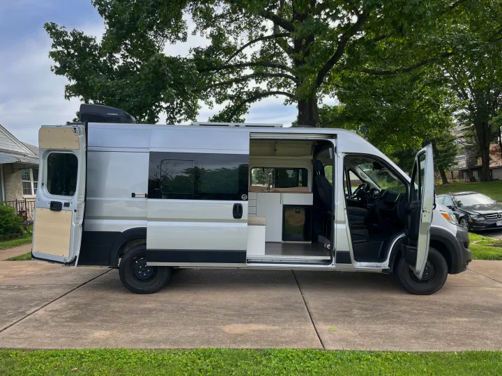 Modern silver camper van for rv rental. Open doors reveal a custom interior with kitchen, fridge, and living area.. Dave & Matt Vans Dave & Matt Vans Class B 2023