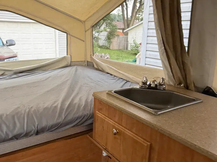 Cozy pop-up camper interior, featuring a bed, sink, and views outside. Perfect for your next RV rental adventure.. Forest River Rockwood Freedom 2013