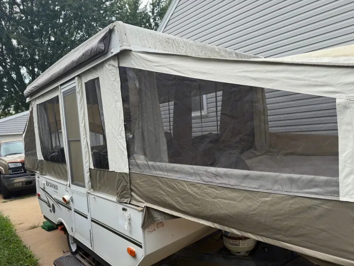 An expanded pop-up camper RV rental, featuring mesh windows, canvas sides, and an awning, ready for outdoor adventures.. Forest River Rockwood Freedom 2013