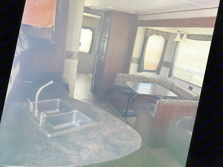 RV rental interior featuring a kitchen with a double sink and a dining area with booth seating and a table. Ideal camper setup.. Crossroads RV Zinger 2012
