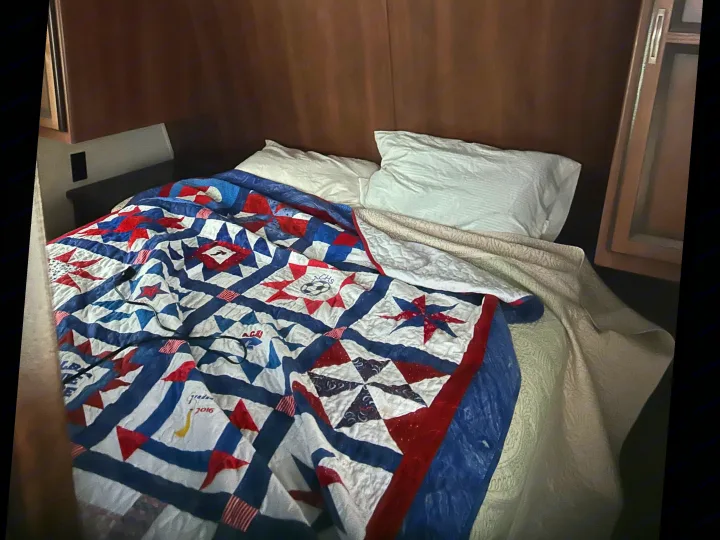 Cozy RV rental bedroom with a personalized patriotic quilt, possibly from a 2016 graduation. Ideal for travel.. Crossroads RV Zinger 2012