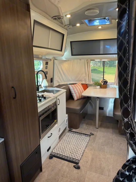 RV rental interior featuring a compact kitchen, dinette, and ample storage for comfortable travel and adventure.. Airstream Caravel 2023
