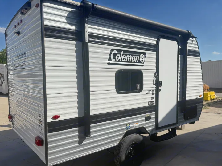 Ready for adventure! This modern Coleman travel trailer RV rental, featuring a sleek grey and white exterior, side door, and awning, awaits.. Keystone RV Coleman 2026