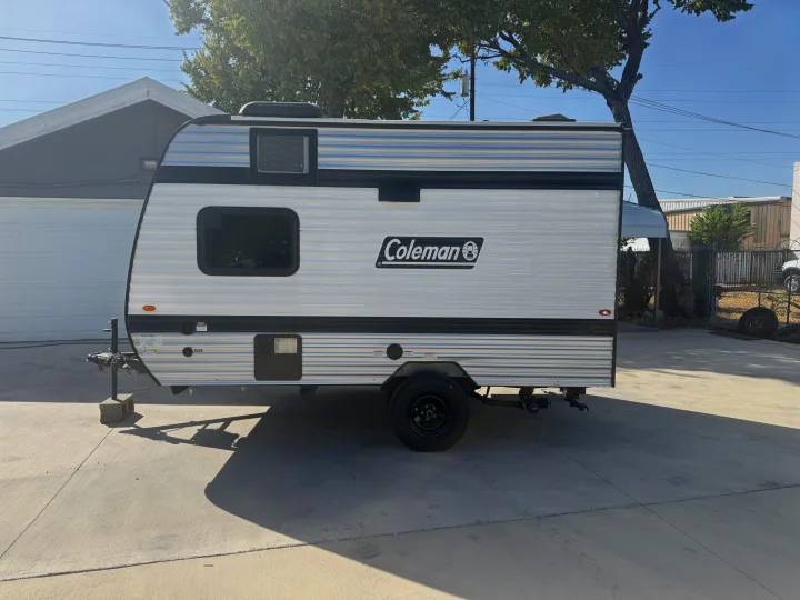This white and silver Coleman travel trailer, ideal for an rv rental, is parked on a sunny driveway.. Keystone RV Coleman 2026