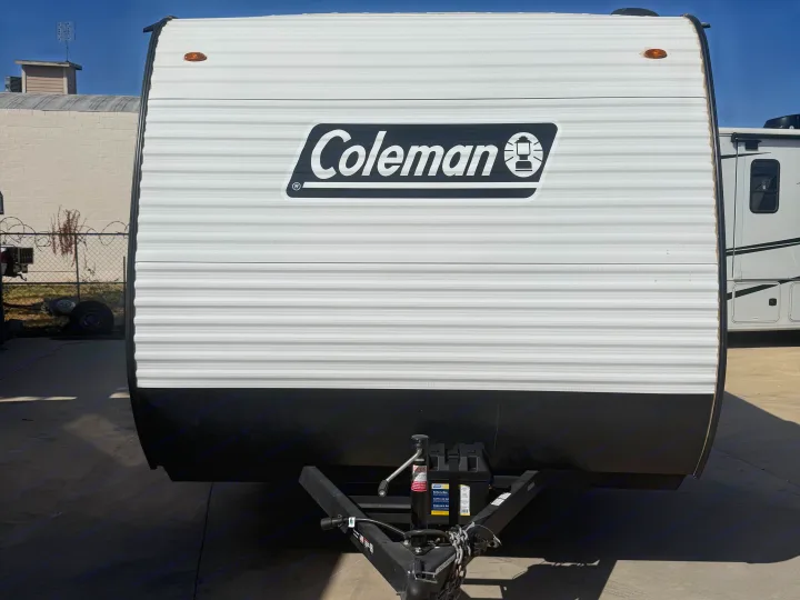 Front view of a white Coleman travel trailer, ideal for rv rental. Shows the brand logo, hitch, and battery box.. Keystone RV Coleman 2026