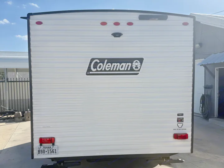 Back of a white Coleman travel trailer, an RV rental with Texas plates and a backup camera.. Keystone RV Coleman 2026