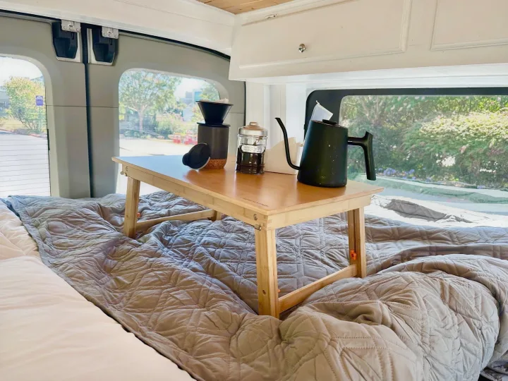 Cozy morning coffee with a pour-over setup and kettle on a bed tray inside an RV rental. Perfect for van life adventures.. Ford Transit 2018