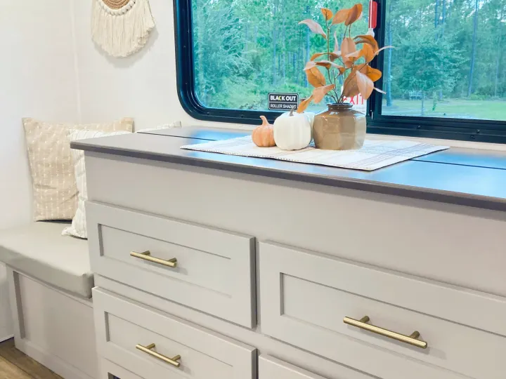 Cozy RV rental interior with modern gray cabinets, autumn decor, comfy bench seating, and a forest view. Perfect for your next adventure!. Alliance RV Avenue 2026