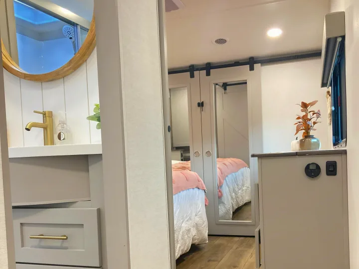 Modern rv rental design: bright bedroom with sliding barn doors, cozy bed, and sleek bathroom vanity.. Alliance RV Avenue 2026