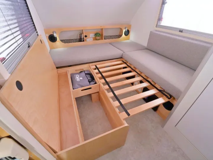 This RV rental interior features a convertible bed with slat base, under-bed storage, and overhead shelving in a compact camper.. nuCamp T@B 2026