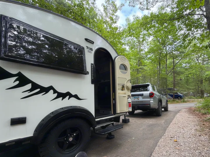 An rv rental teardrop trailer and SUV parked at a lush, wooded campsite, ready for adventure.. nuCamp T@B 2026