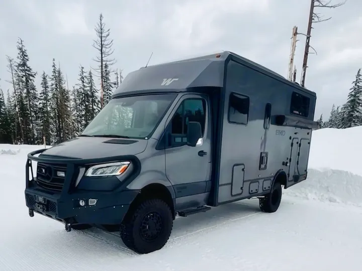 Gray Winnebago EKKO RV rental in a snow-covered forest. Perfect for winter adventure travel.. Winnebago Ekko 2025