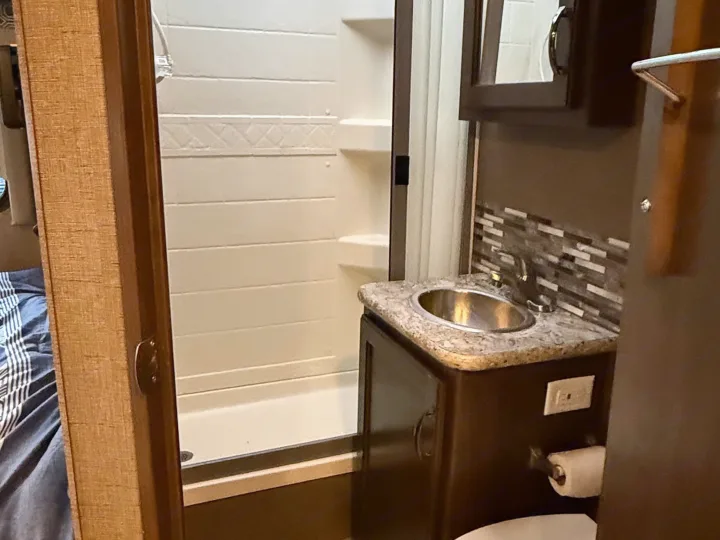 Compact RV rental bathroom featuring a shower, sink, and toilet for comfortable travel.. Thor Four Winds 2018
