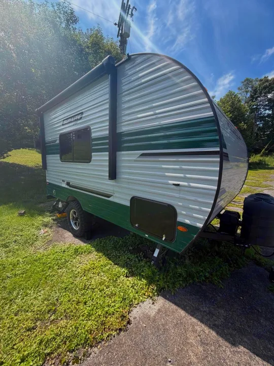 Side view of a green and white "Sun-Lite Sport" travel trailer. Great choice for an rv rental adventure!. Sunset Park RV Sun Lite 2025