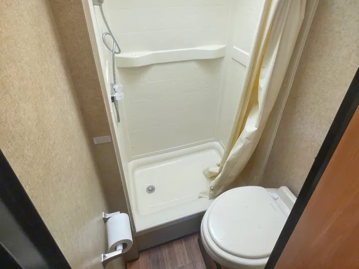This rv rental features a compact bathroom with a small shower stall, toilet, and a toilet paper holder on the wall.. Thor Majestic 2017