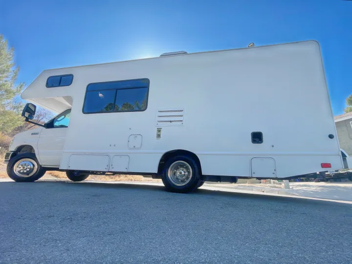 Explore the open road in this white RV rental! Low-angle view of a clean motorhome parked on asphalt.. Thor Majestic 2017