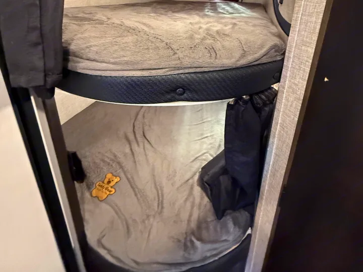 Cozy RV rental bunk beds with gray blankets, black safety rails, and a "Teddy Bear" emblem on the lower bunk.. Jayco Jay Flight SLX Rocky Mountain Edition 2022