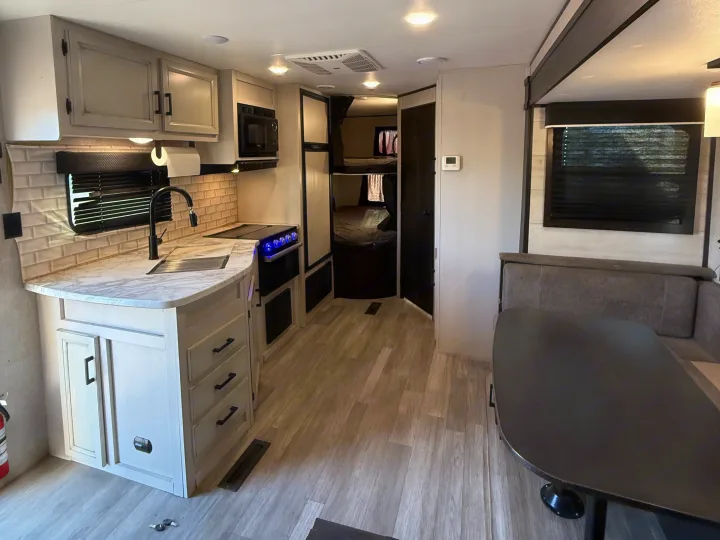 RV rental interior showcasing a bright kitchen with stove & microwave, bunk beds, and dinette. Ready for travel trailer trips.. Jayco Jay Flight SLX Rocky Mountain Edition 2022
