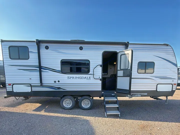 Side view of a silver Springdale travel trailer, an ideal RV rental. Its door is open with steps extended, ready for adventure.. Keystone RV Springdale 2021